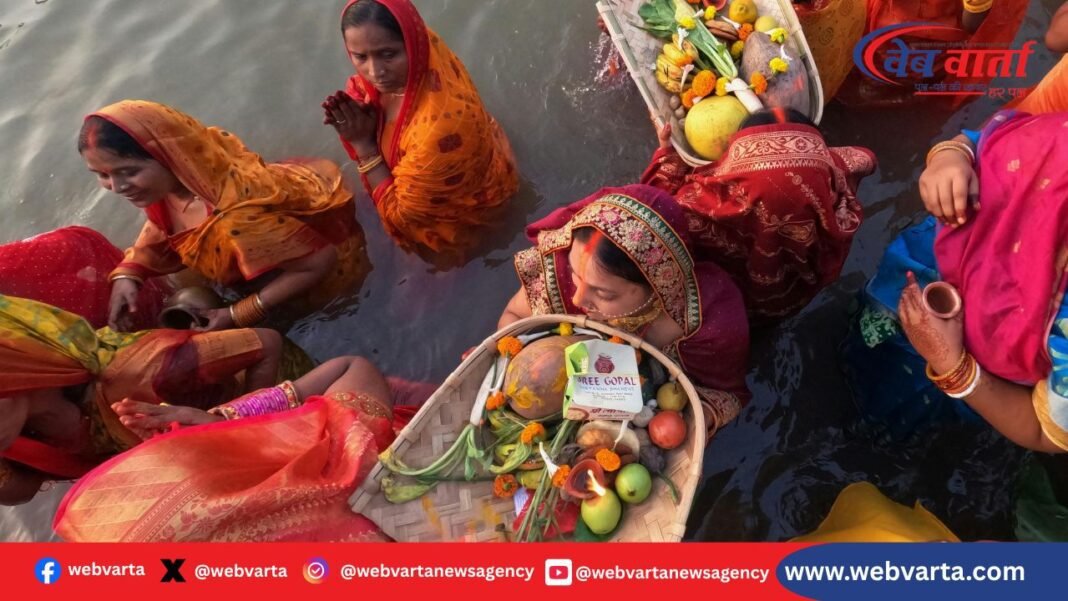 छठ पूजा 2025 के दौरान नदी घाट पर सूर्यास्त में अर्घ्य देते व्रती और उनके साथ दूसरे श्रद्धालु