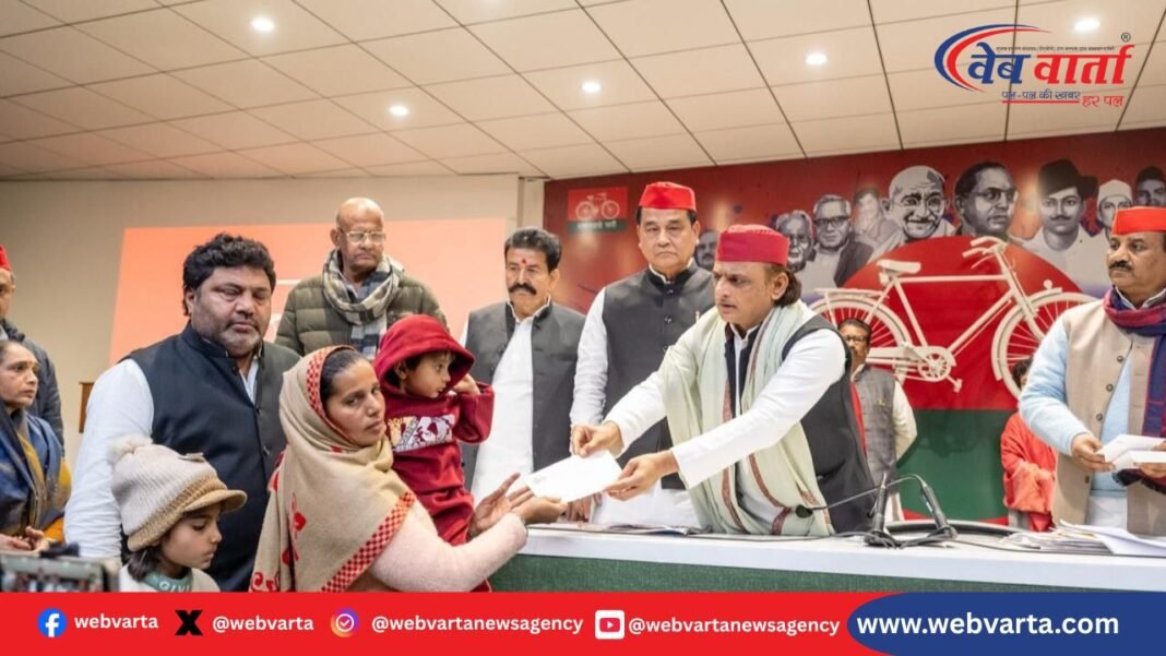 अखिलेश यादव मृतक बीएलओ परिजनों को 2 लाख चेक सौंपते हुए